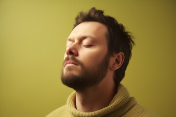 Portrait of a young man with closed eyes on a green background