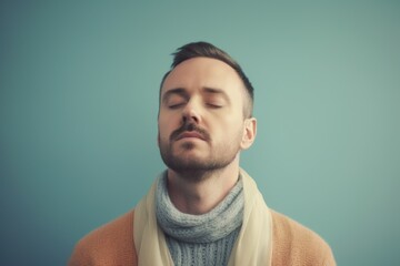 Fototapeta premium Young man in warm clothing with closed eyes. Isolated on blue background