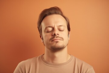 Fototapeta premium Young man with closed eyes on orange background. Portrait of handsome guy