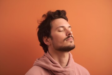 Portrait of a handsome young man in a pink hoodie on a orange background