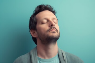 Fototapeta premium Portrait of a young man with closed eyes on a blue background