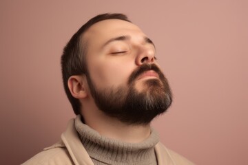 Obraz premium Portrait of a handsome young man with beard and mustache in a beige sweater on a pink background