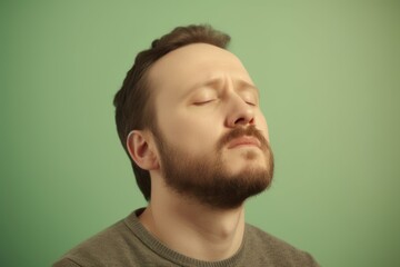 Fototapeta premium Young man with closed eyes on a green background. Toned.