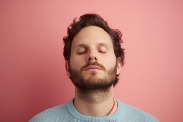 Obraz premium Young man with closed eyes and closed eyes in a blue sweater on a pink background