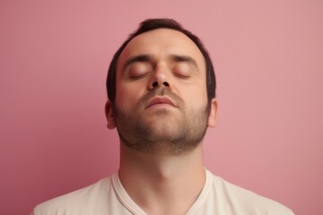 Obraz premium Portrait of a young man with closed eyes on a pink background