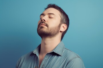 Fototapeta premium Portrait of a handsome young man with closed eyes on blue background
