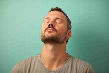Fototapeta premium Portrait of a handsome young man with closed eyes on blue background