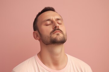 Fototapeta premium Portrait of a young man with closed eyes on a pink background