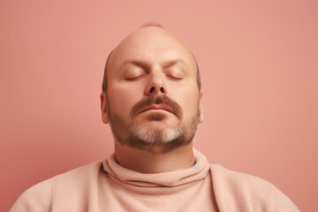 Obraz premium Portrait of a man with closed eyes on a pink background.