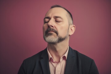 Portrait of a man with closed eyes on a pink background.