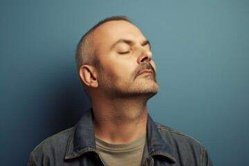Obraz premium Portrait of a handsome young man with closed eyes on blue background