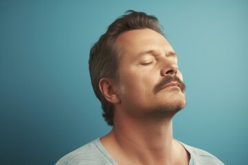 Fototapeta premium Portrait of a handsome man with closed eyes on a blue background