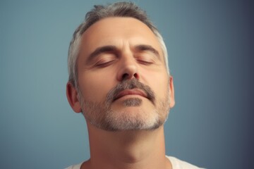 Fototapeta premium Handsome middle-aged man with grey hair and beard on blue background