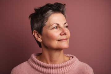 Fototapeta premium Portrait of a beautiful middle-aged woman on a pink background