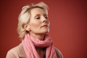Portrait of a beautiful mature woman in a pink scarf on a red background