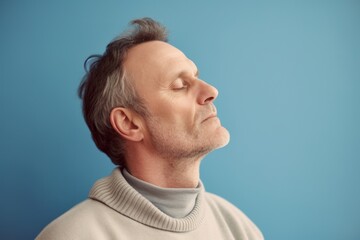 Naklejka premium Handsome middle-aged man with closed eyes on blue background