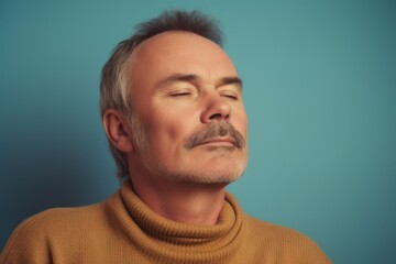 Obraz premium Handsome middle aged man in a yellow sweater on a blue background
