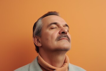 Obraz premium Portrait of a middle-aged man with closed eyes on an orange background