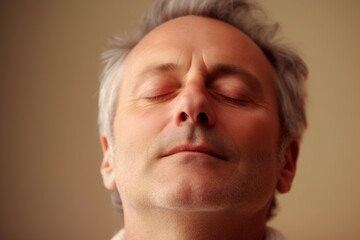 Obraz premium Portrait of a middle-aged man with closed eyes on a beige background