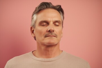 Fototapeta premium Portrait of handsome middle-aged man with closed eyes on pink background