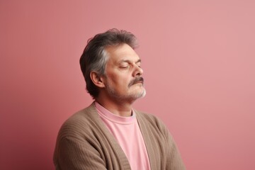 Portrait of a senior Asian man with closed eyes on pink background