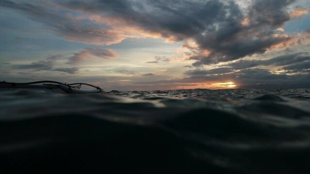 Slow Motion Shot Of Outrigger Boat Floating On Waves Ocean Under Cloudy Sky During Sunset - Oahu, Hawaii