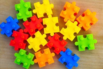 Details of a children's multi-colored constructor are scattered on a wooden table. The concept of the game, recreation, entertainment.