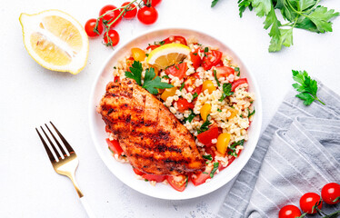 Grilled chicken fillet with bulgur tabbouleh salad with colorful tomatoes, parsley and lemon...