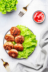 Homemade fried pork and beef meatballs with green lettuce and tomatoes, gray table background, top view