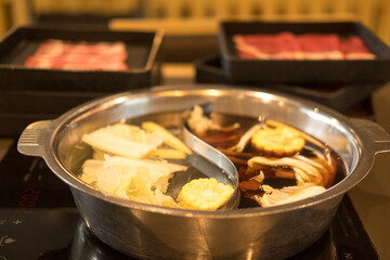 Double flavor hot pot on the table with tray of beef and pork background