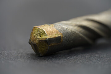 Golden head of concrete drill bit on grey surface. Extreme close up.