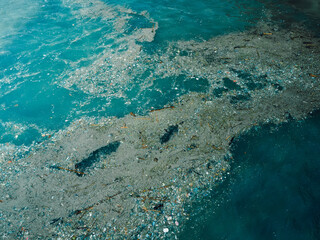 Ocean water and plastic trash in Bali. Aerial view of pollution by plastic rubbish