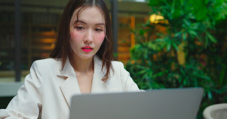 Beautiful business woman working in restaurant. She using laptop to work in restaurant or cafe.