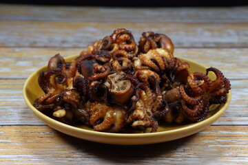 Traditional roasted squid marinated with special sauce serving on the plate. Famous appetizer seafood menu in restaurant.