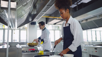 Female asian chef working at kitchen, she cooking food for customer. Chef, Lifestyle, Working, Teamwork and Chef table concept.
