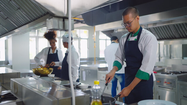 Professional chef cooking at ketchen together. Team of professional cooks in uniform preparing meals for a restaurant in kitchen.