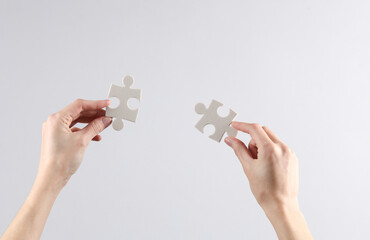 Woman's hands hold puzzle pieces on gray background. Business concept, teamwork