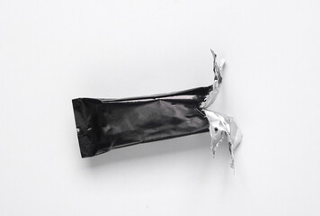 Empty open Black packaging of a chocolate or protein bar on gray background