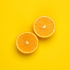 Fototapeta premium Two ripe slices of arpelsin on a yellow background. Top view
