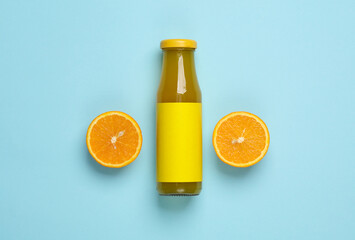 Bottle of orange juice with half a juicy orange on blue background. Top view