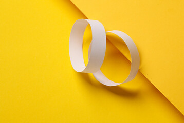 Two white paper bracelets on a yellow background