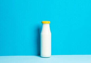 Glass bottle of yogurt on a blue background