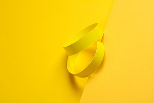 Two yellow paper bracelets on a yellow background
