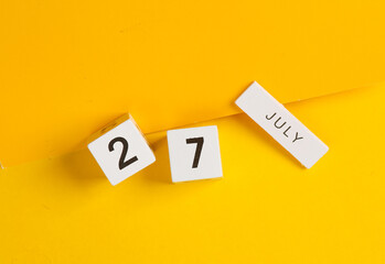 White calendar cubes with date july 27 on yellow background. Creative layout