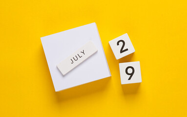 White calendar cubes with date july 29 on yellow background. Creative layout