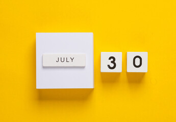 White calendar cubes with date july 30 on yellow background. Creative layout