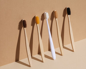 Plastic and wooden toothbrushes on a beige background with a shadow. Eco concept, plastic free, dental care. Creative layout