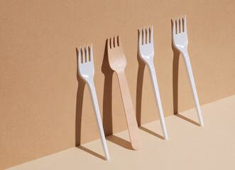 Plastic and wooden forks on a beige background with a shadow. Eco concept, plastic free, food. Creative layout