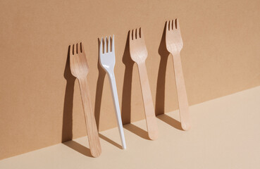 Plastic and wooden forks on a beige background with a shadow. Eco concept, plastic free, food. Creative layout