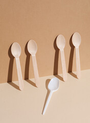 Plastic and wooden spoons on a beige background with shadow. Eco concept, plastic free, food. Creative layout